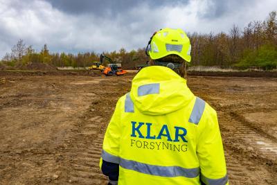 Ryggen af en medarbejder fra KLAR Forsyning i gul jakke og hjelm