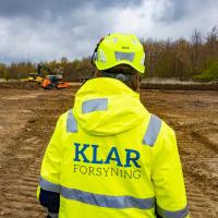 Ryggen af en medarbejder fra KLAR Forsyning i gul jakke og hjelm